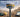 A GNSS receiver standing in front of surveying equipment with a construction site in the background and satellites in the sky.