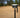 A GNSS antenna attached to a GNSS receiver standing on a pole with a sandy background and palm threes behind.