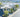 A white drone hovering over a city landscape.